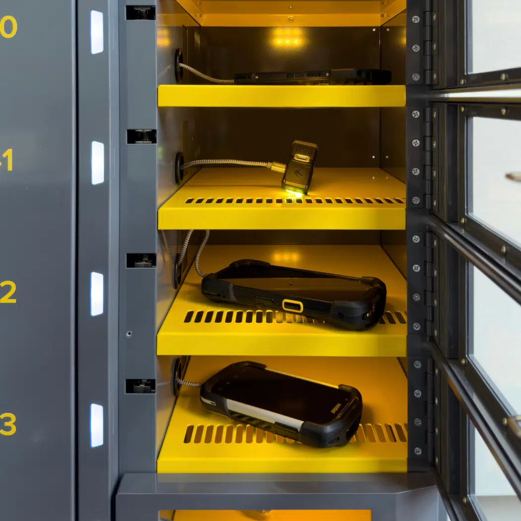 ARC-OpenLockers Close-up of open ARC kiosk locker bays with assortment of handheld enterprise devices securely charging inside numbered compartments.